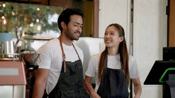 生意伙伴帅哥和漂亮的亚洲女孩两个人站在一起谈论开这家咖啡店的事以极大的决心开咖啡店赚钱