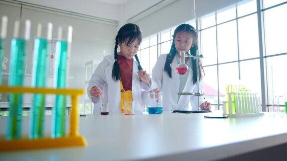 小学生科学实验学校化学实验室的STEM教育小女孩在烧杯中混合化学物质