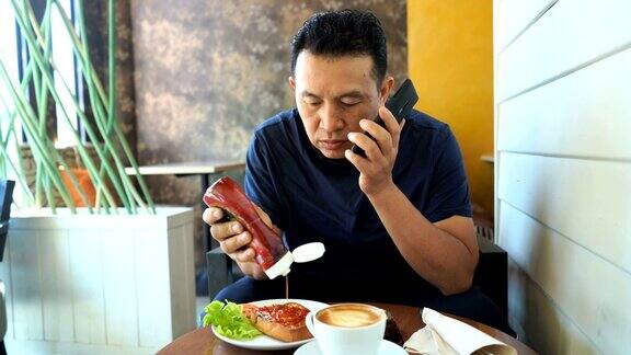 成熟的亚洲男人在咖啡店使用电话