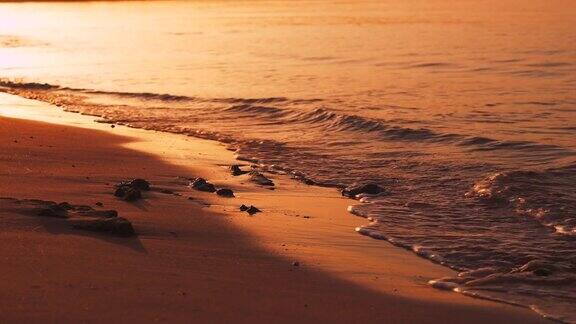红色日落时沙滩上海浪边缘的特写热带平静复制空间背景