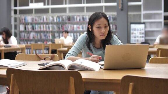 亚洲年轻女学生在图书馆看书和做笔记