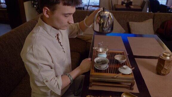 男子将热水从茶壶中倒进碗中并加入干茶