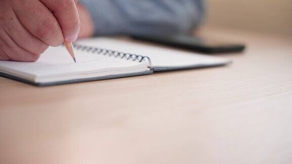 一个无法辨认的男人用钢笔在笔记本纸上写备忘录