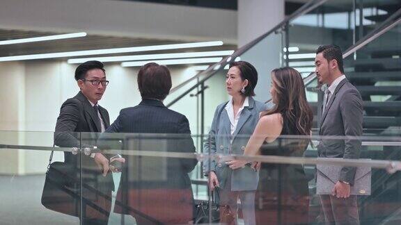 下班后亚洲华人穿着工作服在办公楼走廊上交谈