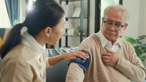 特写亚洲女性专业个人护理人员照顾老年男性使用血压计检查血压监测器在家里的沙发