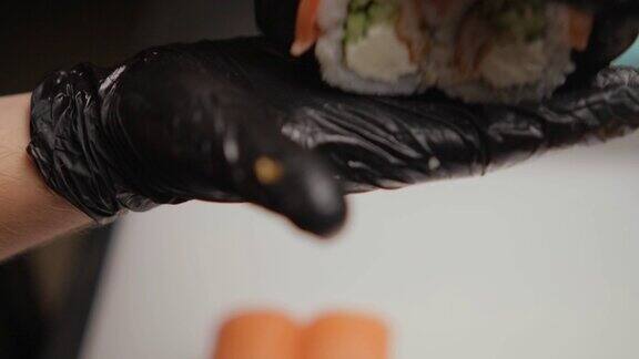 一位戴着黑色乳胶手套的厨师在他的手掌上演示现成的寿司