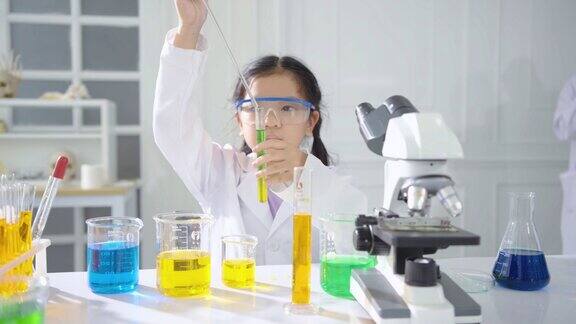 在实验室里练习科学的初级科学家的肖像兴奋的孩子在课堂上把化学成分一件一件地混合做实验