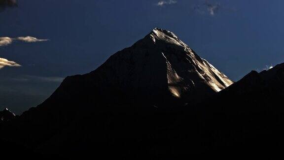 白雪皑皑的山顶上夜幕降临夕阳下的冰闪着光山顶上的云在旋转