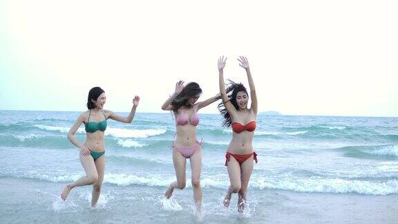 一群快乐的女孩朋友在沙滩上玩水美丽的亚洲女孩在暑假庆祝和放松