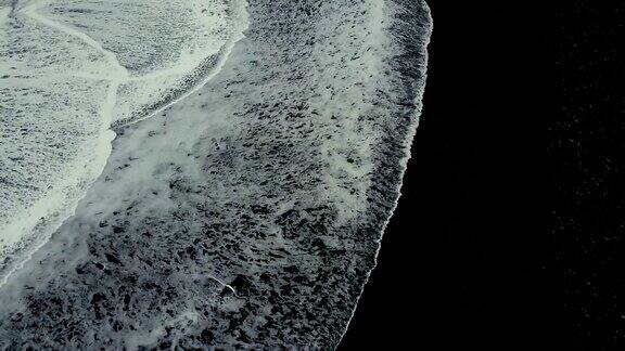 顶部鸟瞰在冰岛的黑色火山海滩海岸上的巨浪