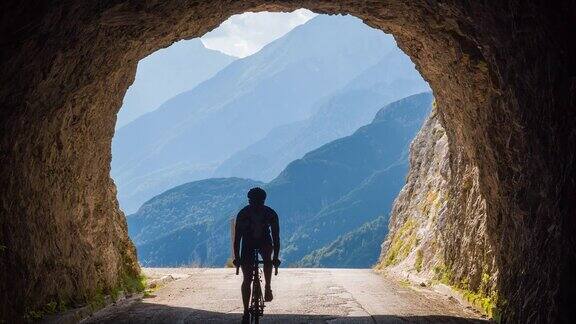 骑公路自行车的人进入山区的岩石隧道