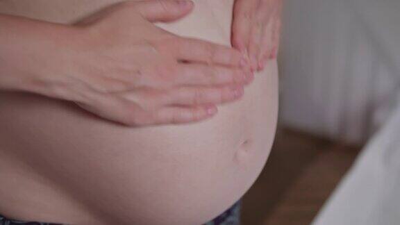 一名年轻的孕妇在她的肚子上擦霜