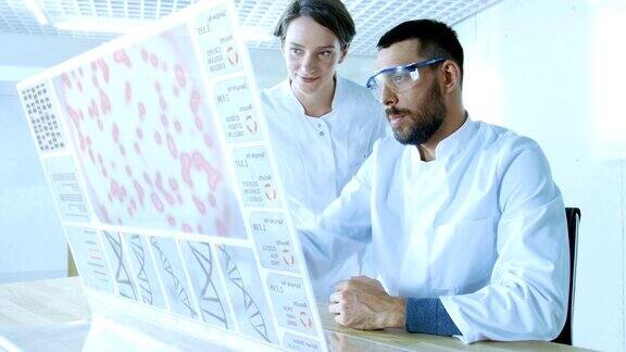 在未来的实验室里男科学家和女科学家一边在透明显示计算机上工作一边交谈屏幕显示人类DNA序列