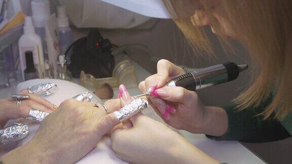 美容院的美甲师用手指甲器给女性抛光表面指甲硬件修指甲
