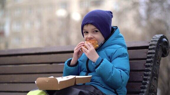 饥饿的孩子在户外吃双层芝士汉堡