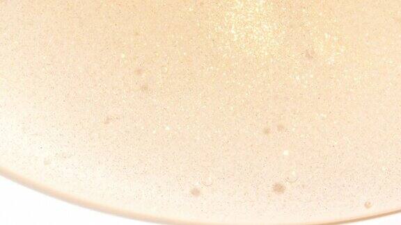 透明黄色化妆品液体凝胶的微距镜头泡沫在白色表面流动的奶油天然有机化妆品医药