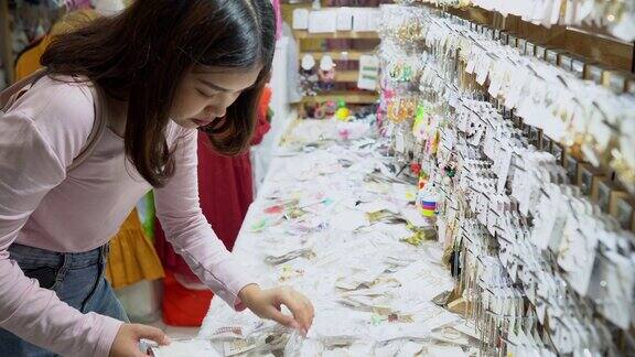 年轻美丽的亚洲女人在购物中心选择耳环