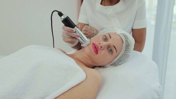 美丽的女人躺在水疗中心做面部护理美容和SPA概念