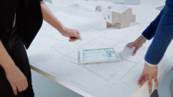 女性建筑师使用平板电脑讨论平面图握手