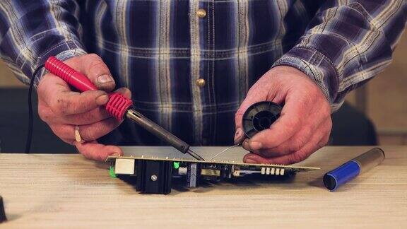 一个大师级的特写镜头一个男人正在焊接一个电子电路板