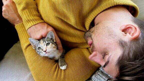 年轻人躺在沙发上抚摸着他的宠物猫怀里抱着她4K4K