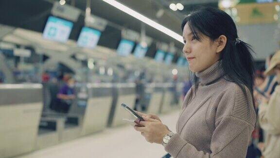 度假时在机场等待起飞的亚洲女性她在智能手机上查询时间等待她的航班