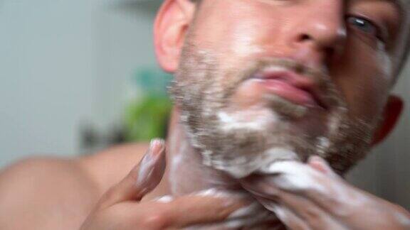 年轻英俊的男子用理发店特制的剃须香波擦洗他未剃的胡子早上例行野蛮男人在浴室皮肤护理和胡须卫生特别男性面部毛发治疗在家时尚剃胡子