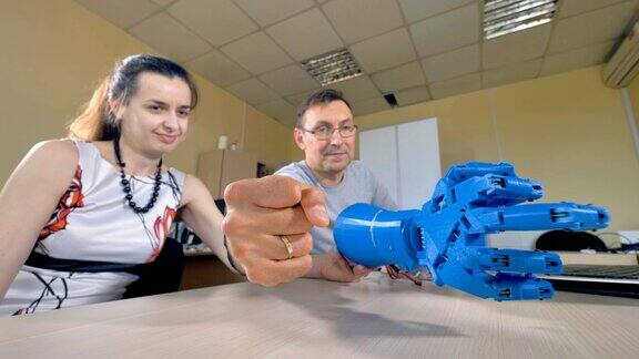 一位工程师向一位女助手展示仿生手臂的运动