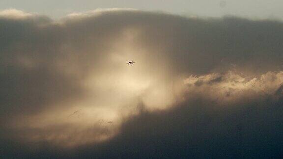 一架商用客机在乌云密布的日落天空中飞行的剪影