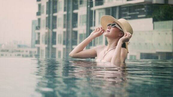 亚洲旅行者旅游比基尼女人戴着帽子的女孩放松的假期快乐的假期在酒店的游泳池