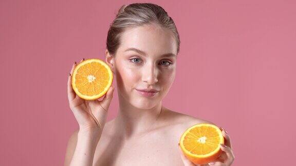一个快乐的年轻女子正在摆姿势手里拿着橘子