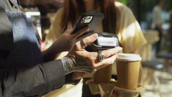 亚洲顾客在咖啡店购买咖啡后用手机扫描二维码支付