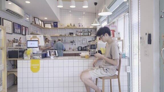 一名年轻的亚洲男子大清早坐在吧台边喝咖啡