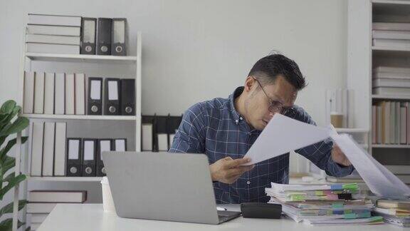 亚洲商人忙于处理财务文件工作压力大疲惫的员工在办公室超负荷工作