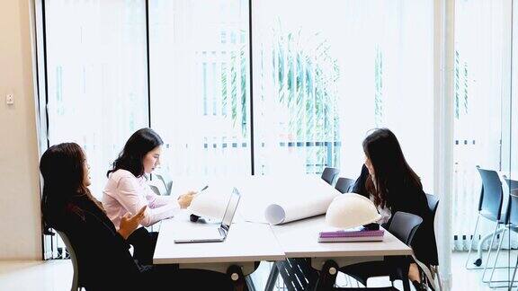 亚洲商人和工程师团队使用笔记本给商业伙伴讨论文件和想法商务女性在工作中微笑