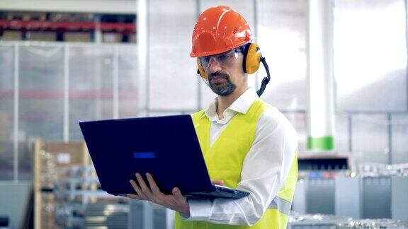 一名男性工厂工人穿着防护服使用笔记本电脑的工作过程