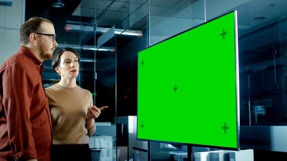 深夜男和女专家在会议室讨论模拟色键绿屏电视