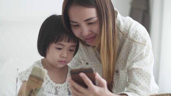 母亲和女儿在卧室里使用智能手机