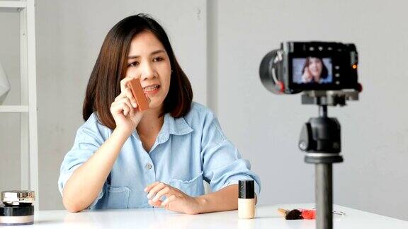 年轻的亚洲女性影响美容时尚博主录制视频展示她的产品拍摄相机