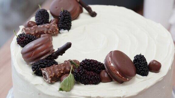 这个女人把各种各样的巧克力和浆果放在奶油上装饰白蛋糕的顶部