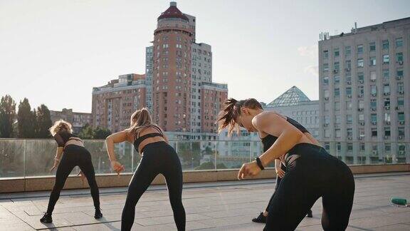 一群女孩在一位年轻女教练的指导下跳尊巴舞年轻活跃的女性在开放的城市空间或广场上锻炼