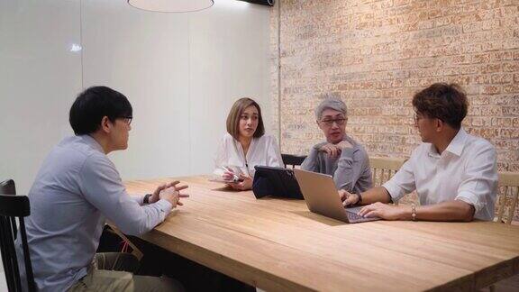 年轻的亚洲人与招聘团队和高级经理在办公室会议室面试