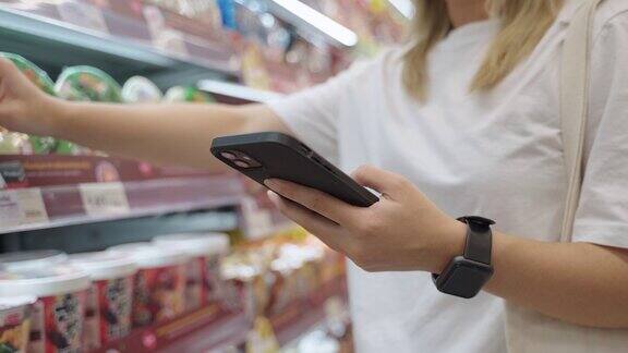 一名亚洲女性在超市买东西时使用智能手机