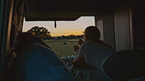 日落时分WS夫妇在草地上停着一辆露营车的小木屋里休息