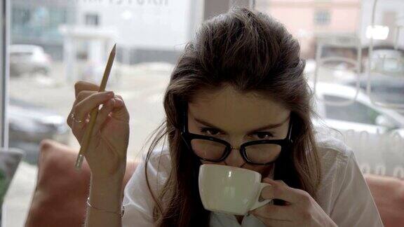 漂亮的白人女孩戴着眼镜在咖啡馆工作喝咖啡