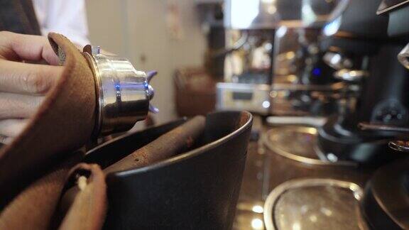 一名咖啡师正在使用咖啡机将咖啡粉压实以便在咖啡馆煮咖啡