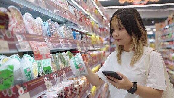 一名亚洲女性在超市买东西时使用智能手机