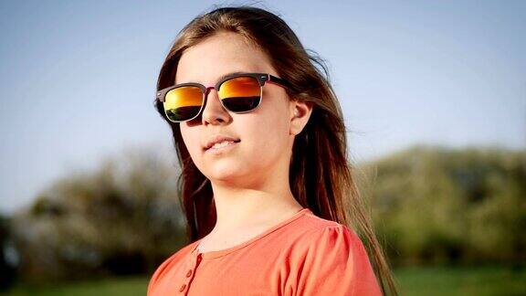 一个戴着太阳眼镜的女孩在日落时的肖像