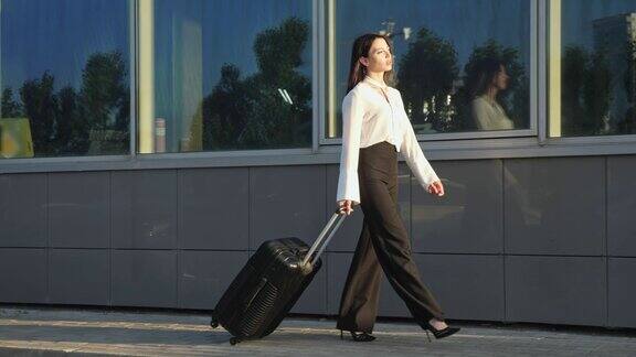 女商人提着行李箱经过机场航站楼