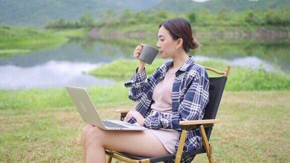 4K亚洲女性在暑假野营时喝着咖啡用笔记本电脑工作